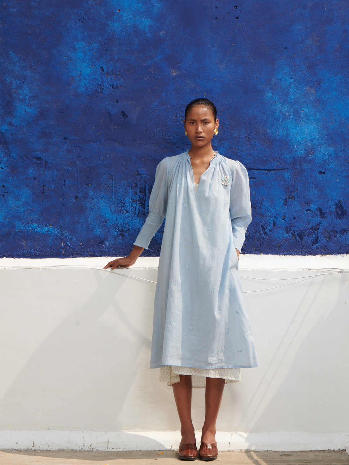 Light blue, smocked neck, geranium dress in mulmul cotton with hand embroidered detail, paired with a halter neck chemise.